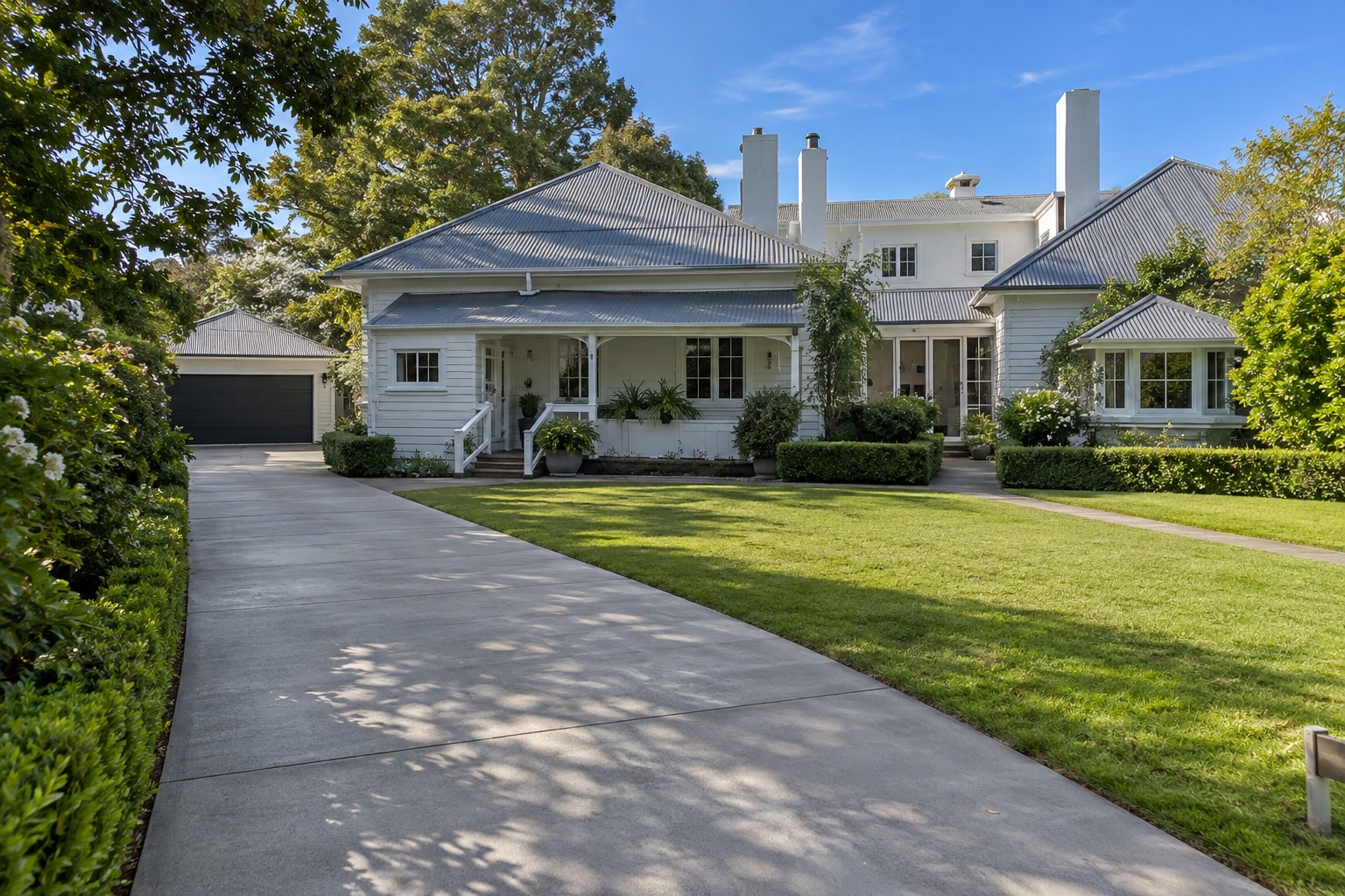 Long plain concrete driveway leading to a detached garage in Hobart