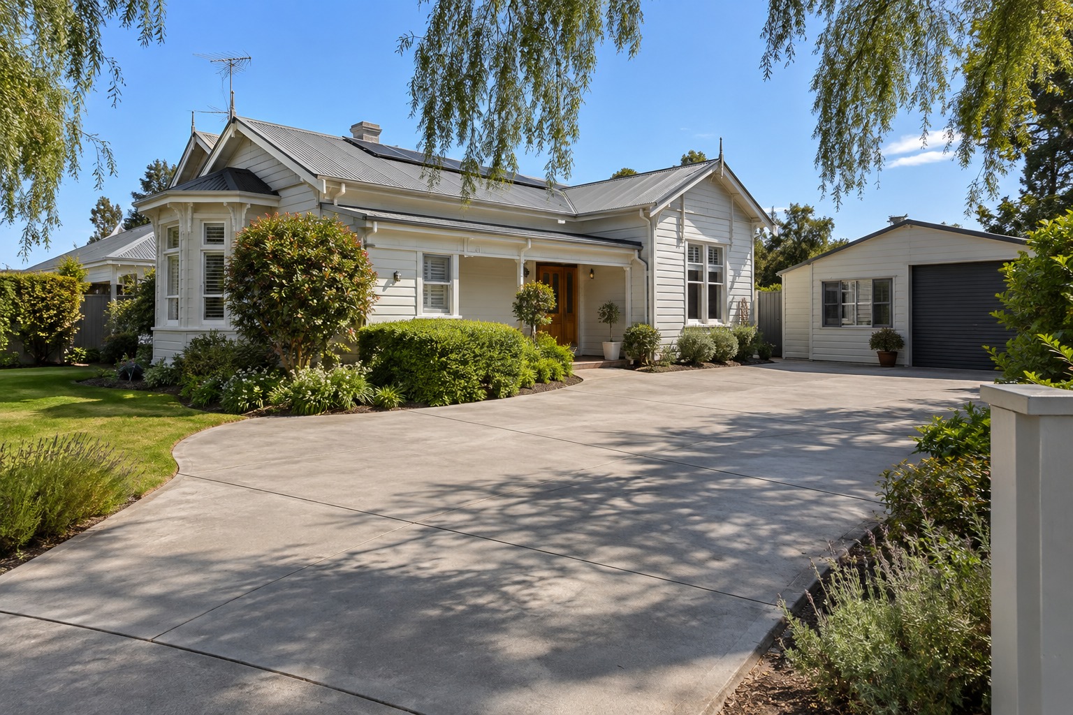 Wide jointed concrete driveway curving past a weatherboard home in Hobart